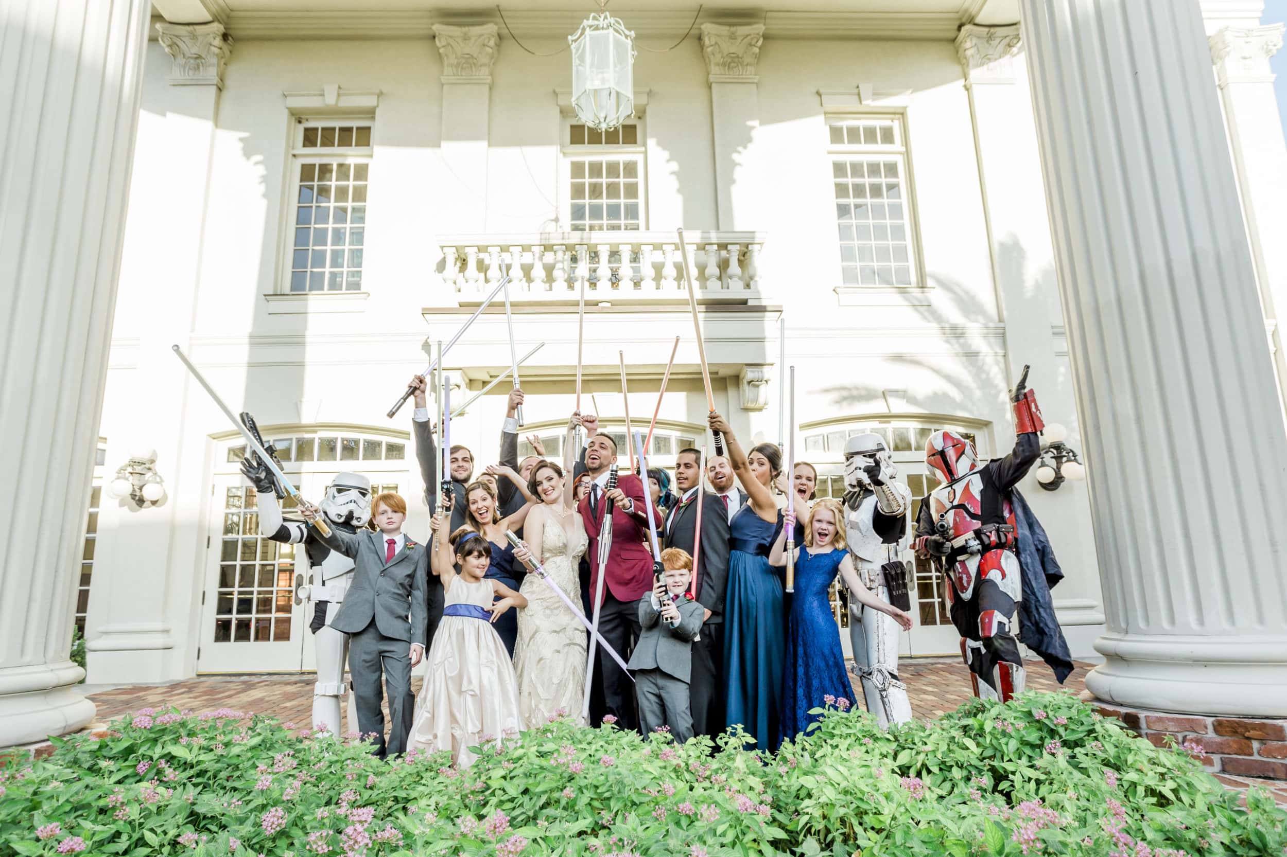 formal bridal party with light sabers with large white building with large white columns in background at Star Wars Wedding