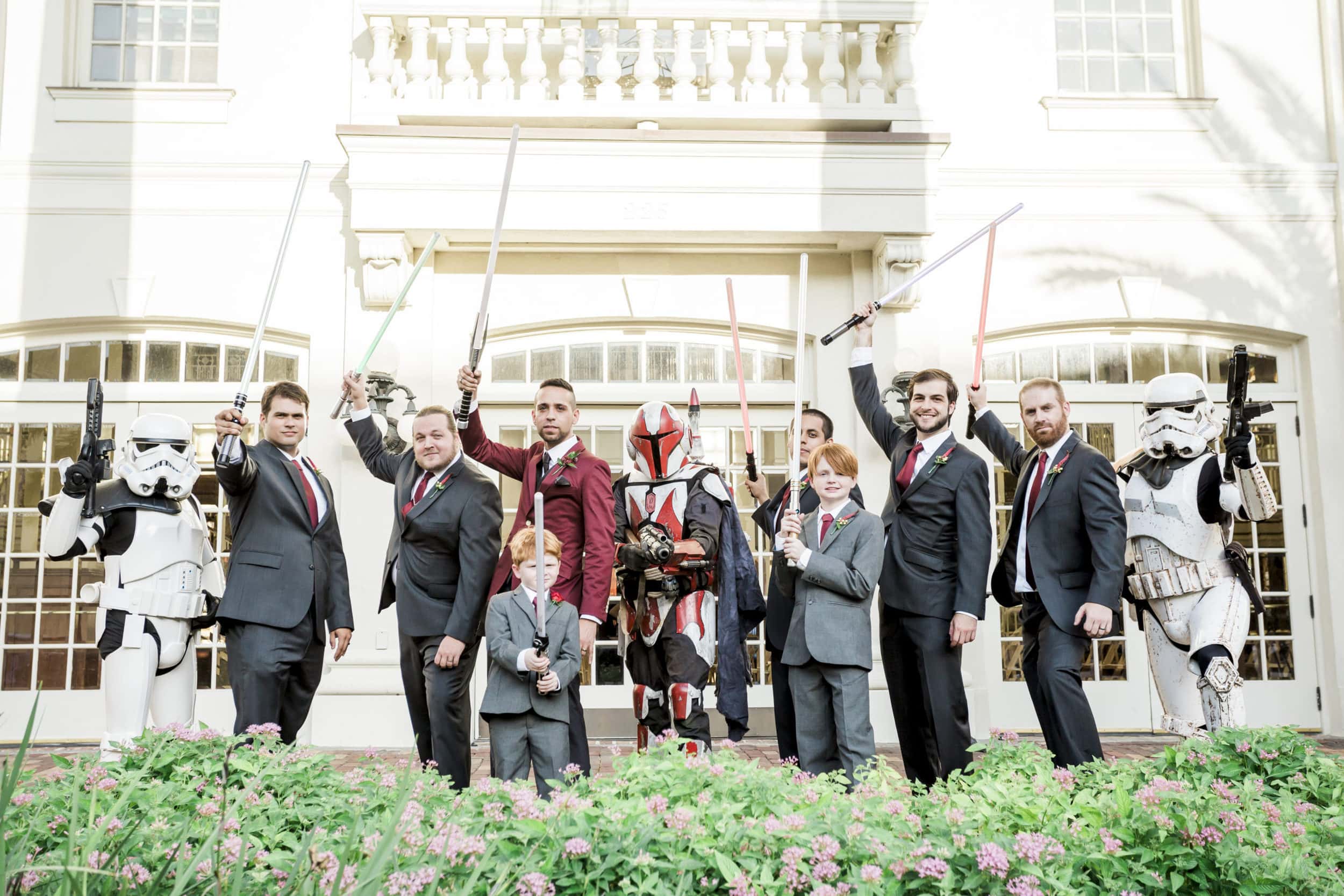 groomsmen with grey suits with lightsabers with large white mansion in background at Star Wars Wedding