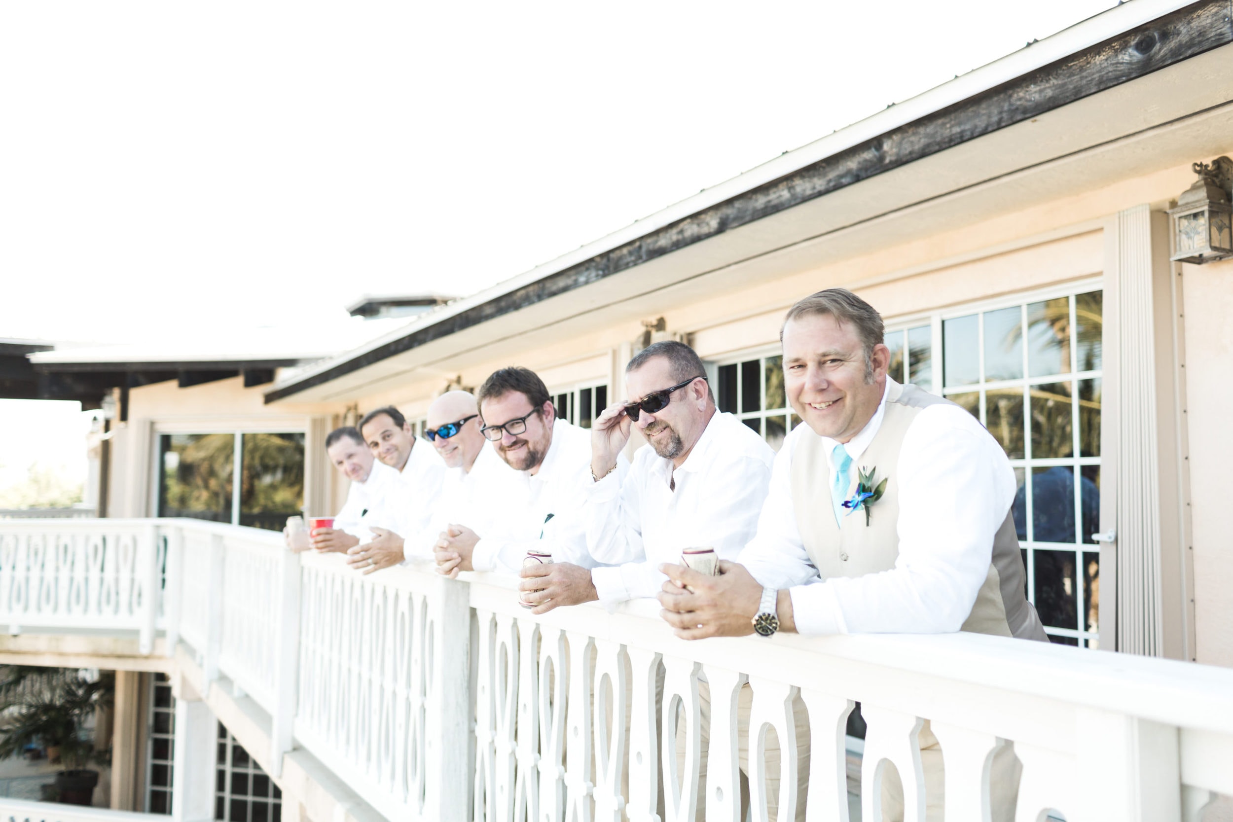 groomsmen with tan pants and white shirts with teal blue flowers at Coconut Cove Resort Wedding