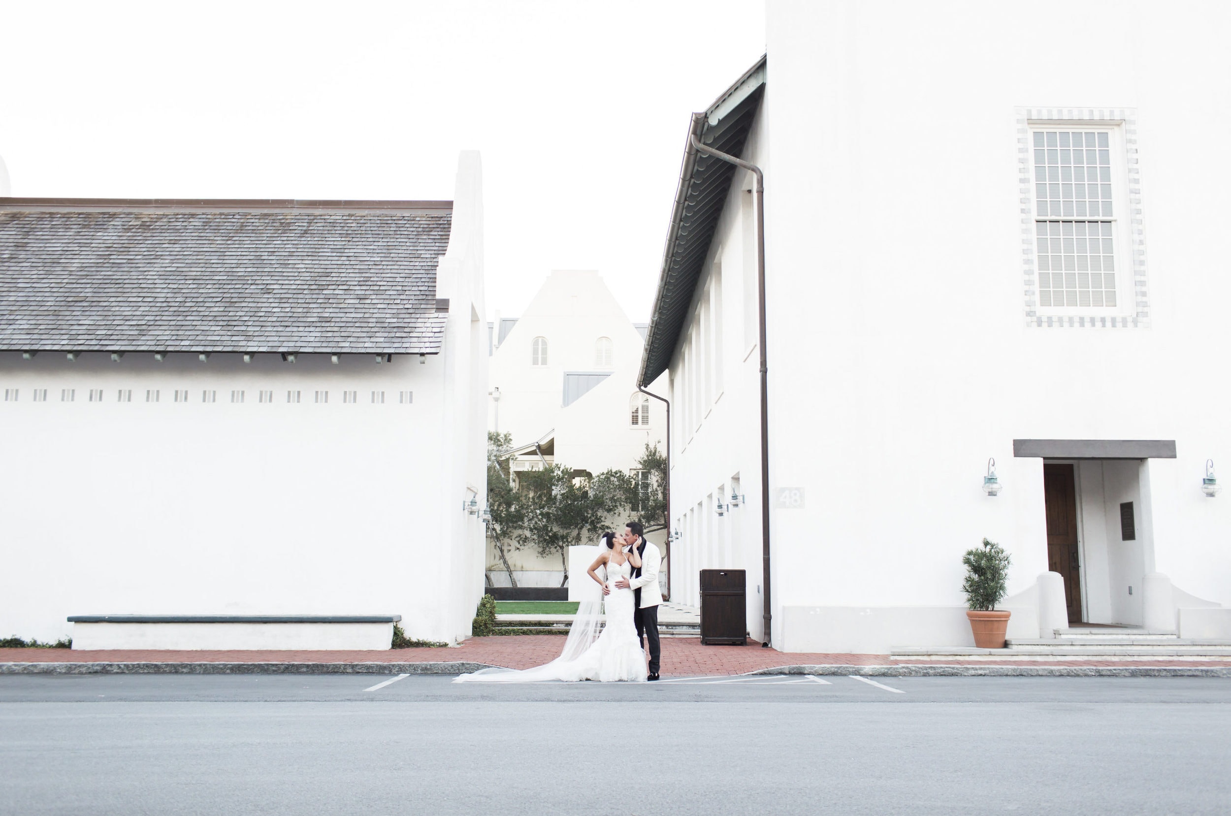 bride and groom kissing between all white buildings in rosemary beach florida