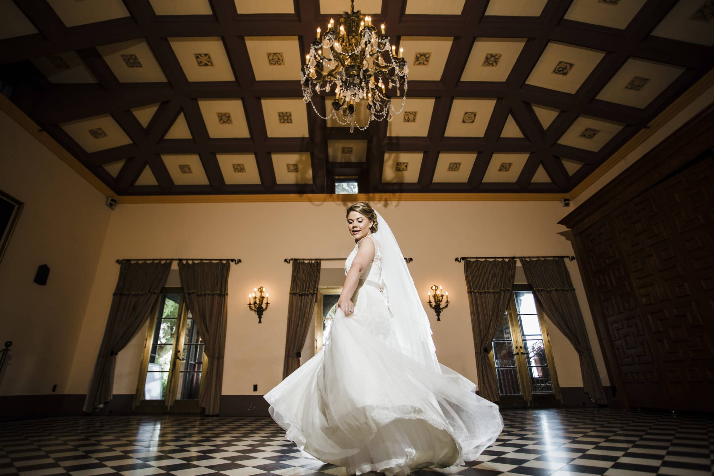 bride in white dress with black and white checkered floor with chandelier at deering estate wedding