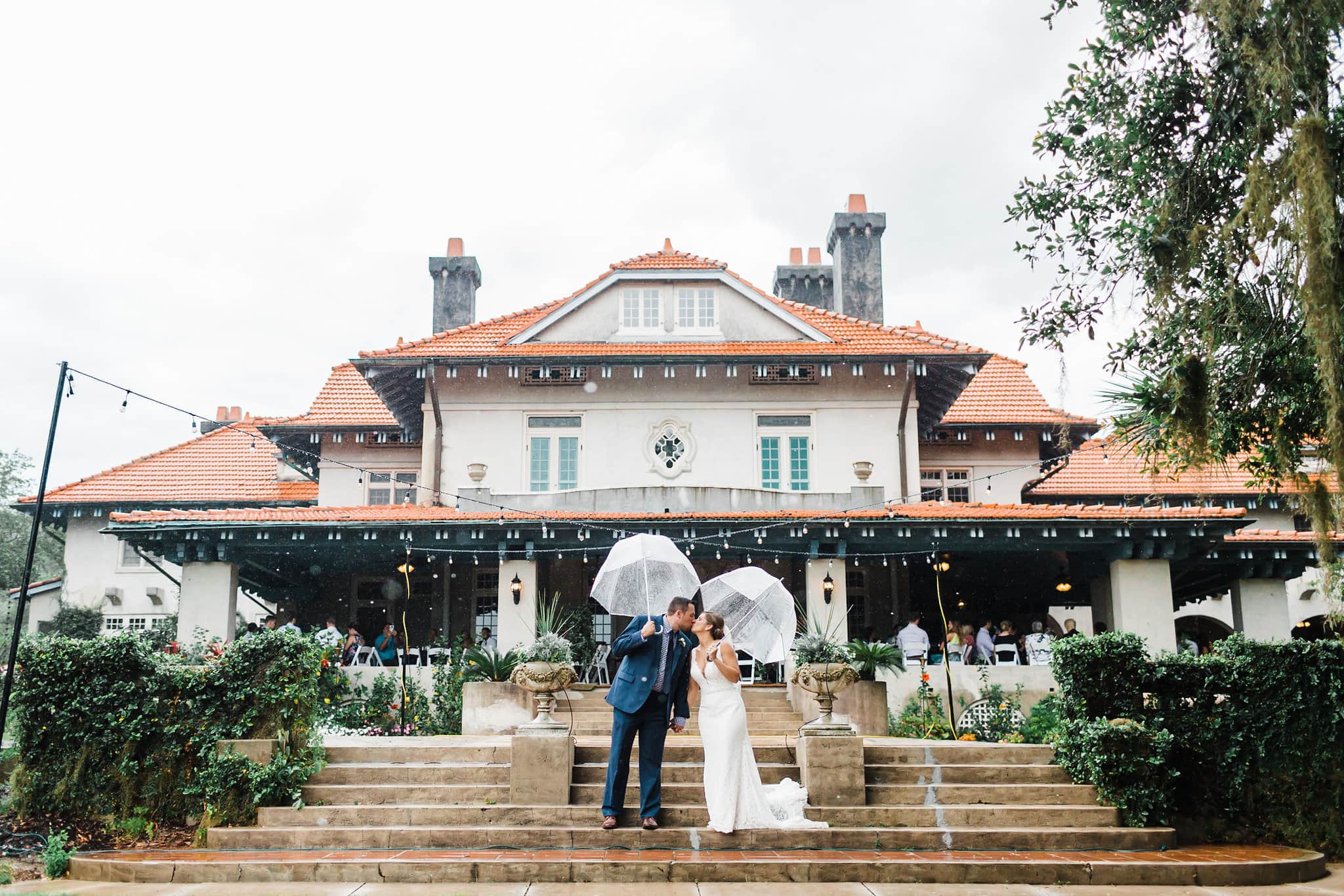  bride and groom kissing under umbrellas at rainy sydonie mansion wedding