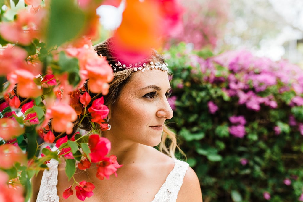 bride with headpiece standing in the middle of red, pink, and purple tropical flowers at a florida keys wedding at coconut palm inn