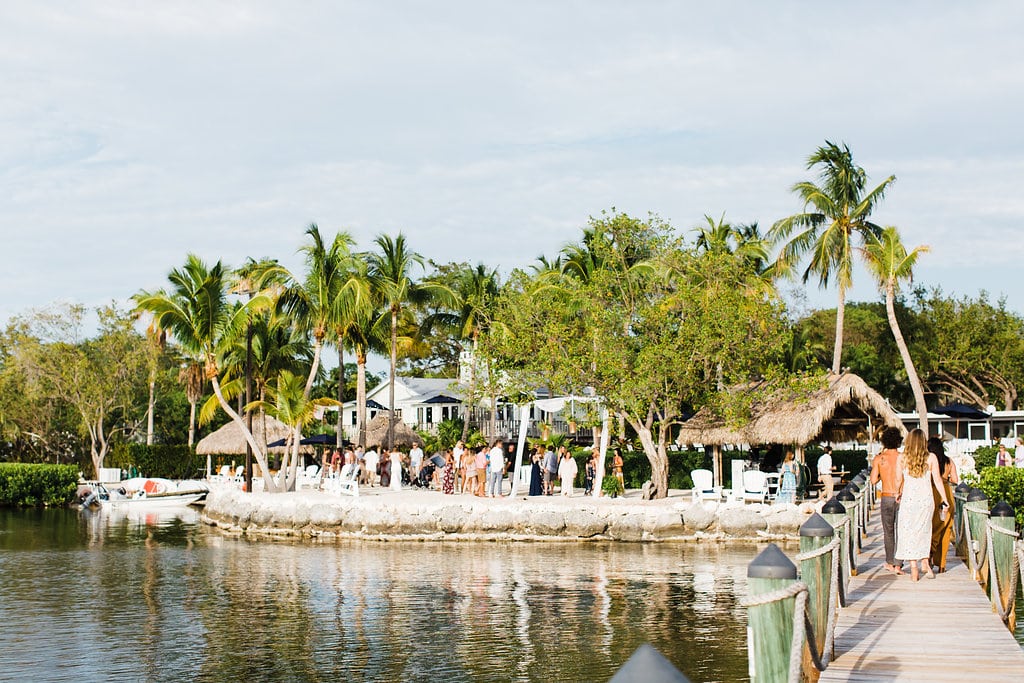 wide shot of Florida Keys wedding at coconut palm inn that displays island and cove where ceremony is held, palm trees, and the dock that leads out into the ocean