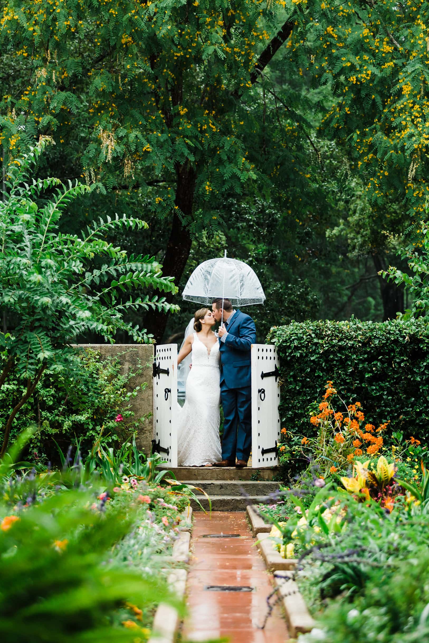 orlando garden wedding Sydonie mansion with bride and groom kissing under clear umbrella