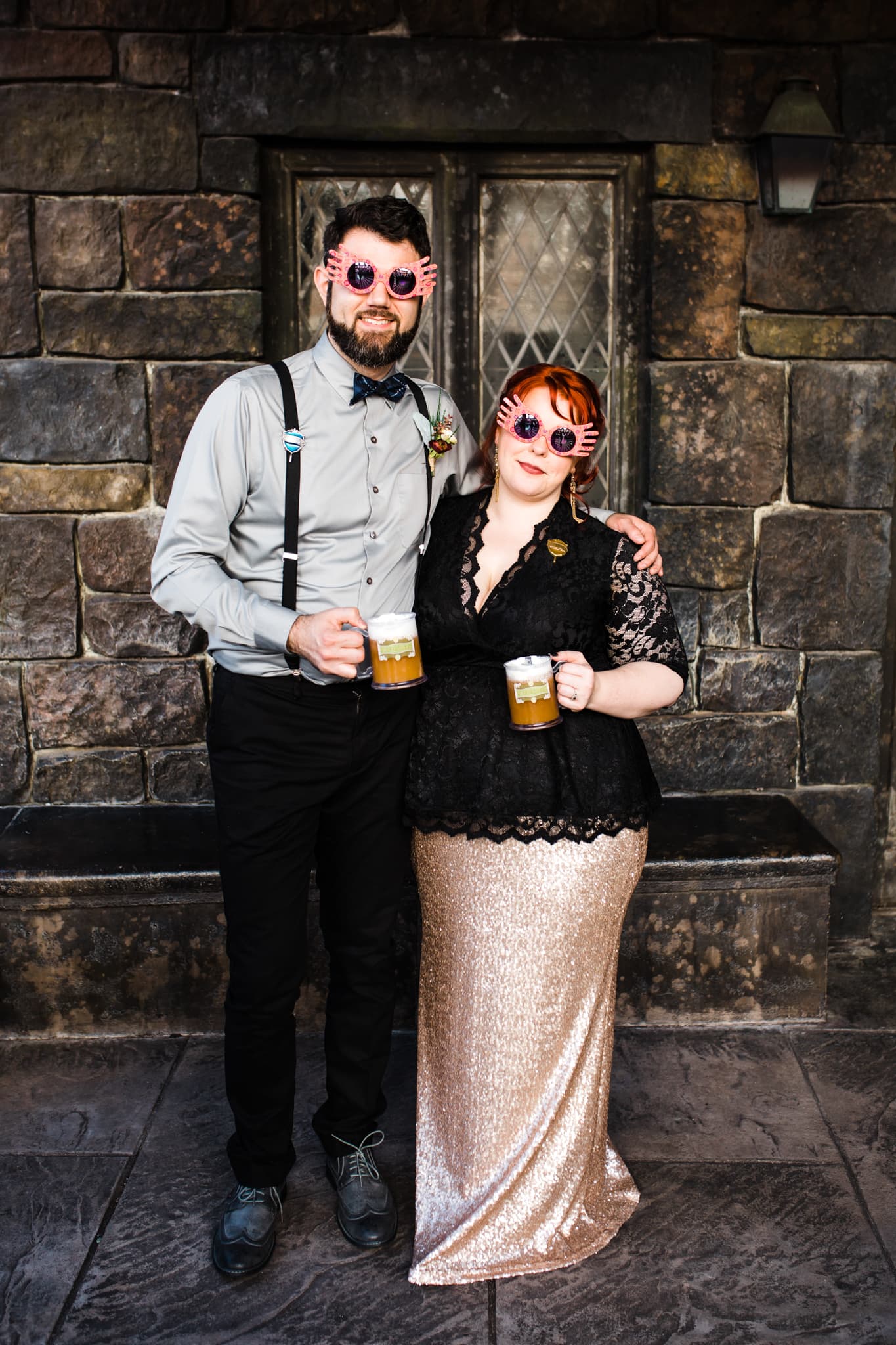 couple drinking butter beer and wearing pink sunglasses at hogsmeade at Hogwarts universal orlando during engagement session