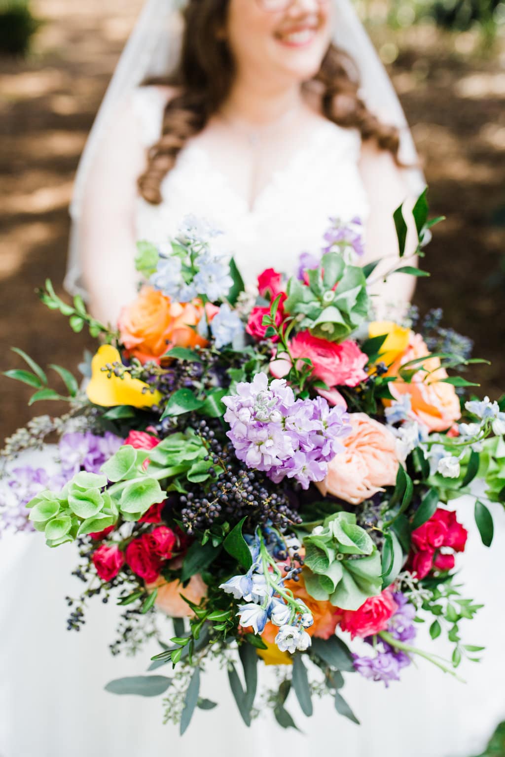 wildflower wedding bouquet with purple, blue, yellow, orange, red, and blue flowers and light greenery