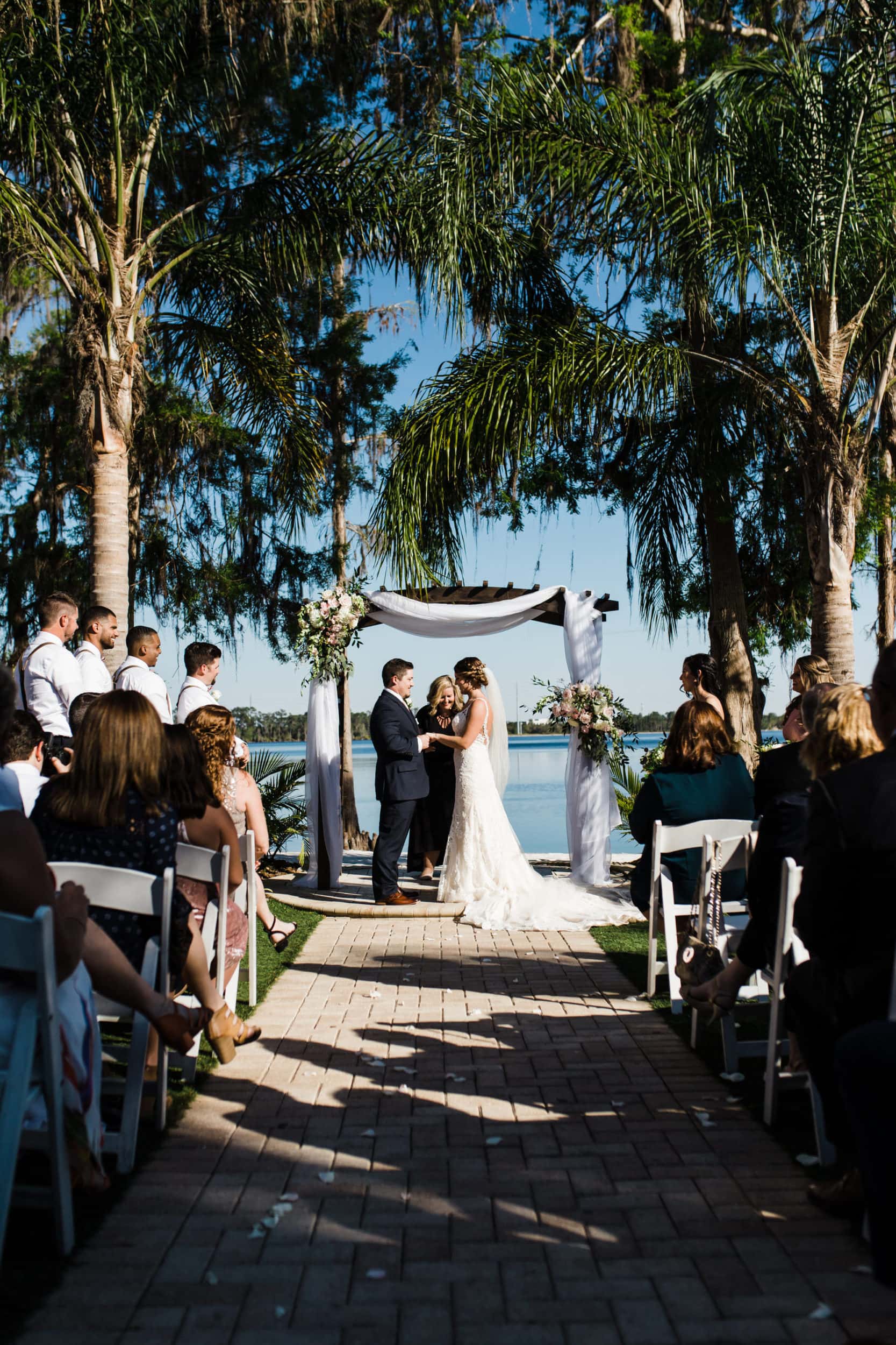 bride and groom underneath canopy of palm trees during paradise cove wedding 