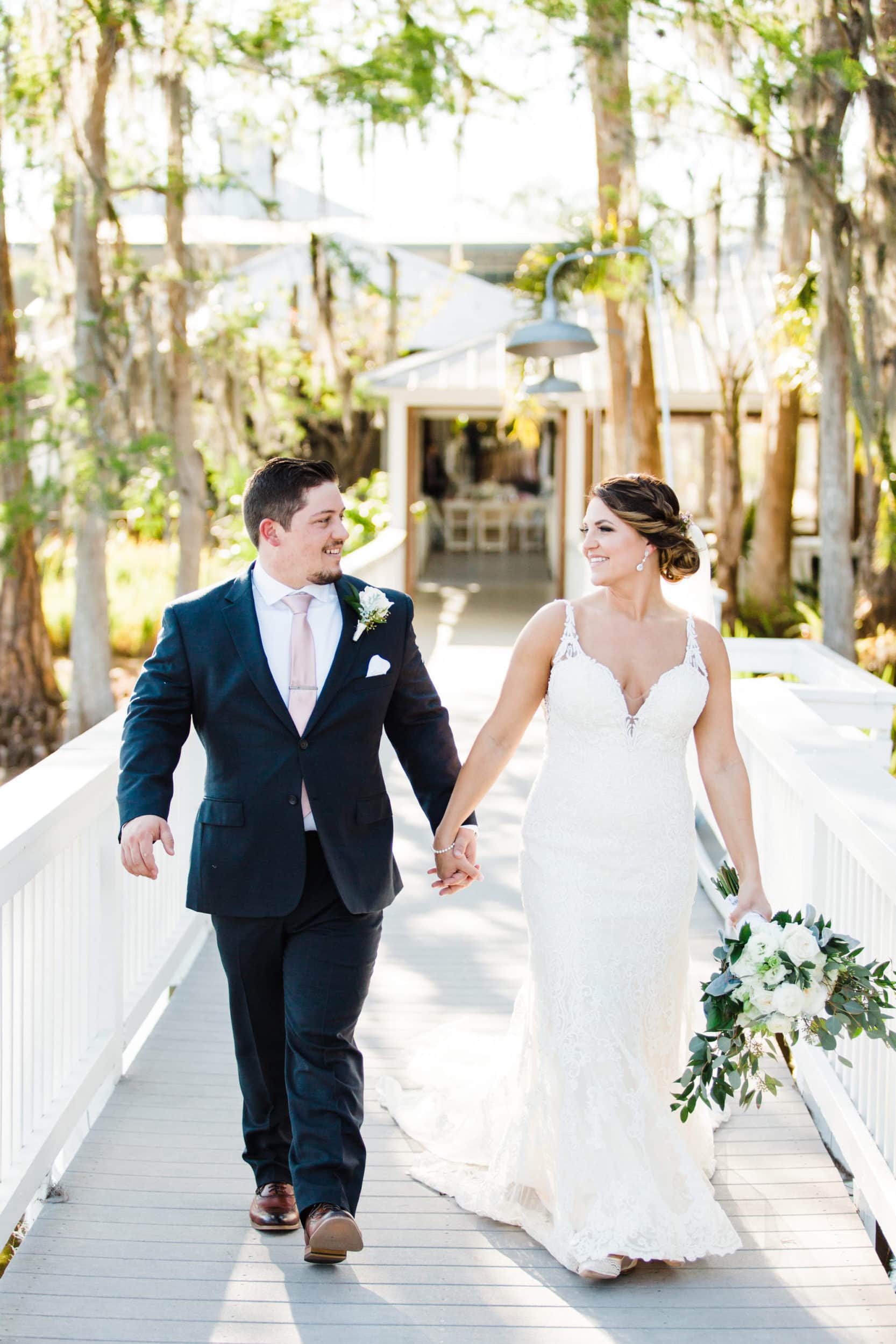 bride and groom walking down the dock at paradise cove together holding hands