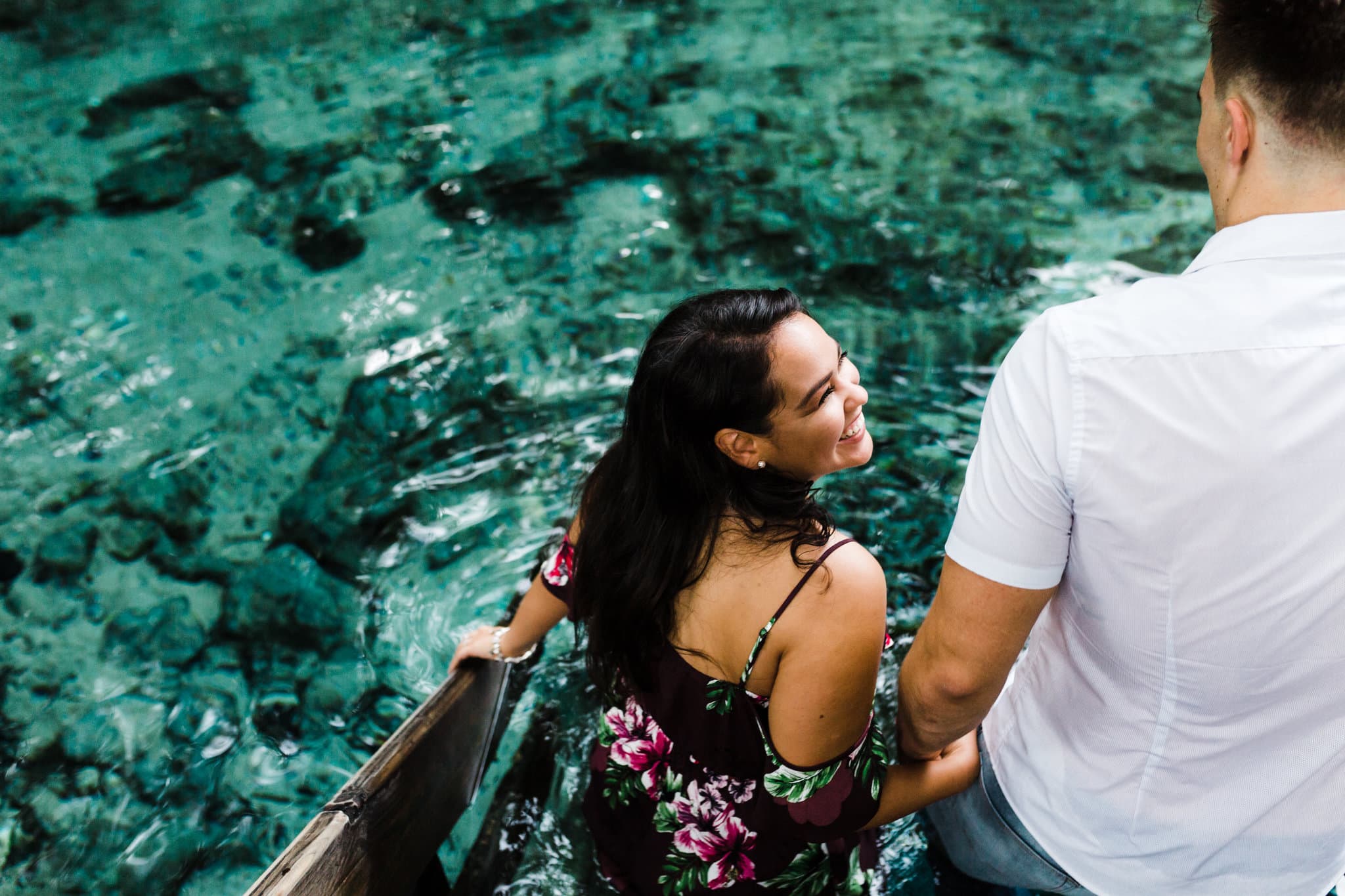 girl leading fiancé into the blue springs water for ginnie springs engagement session
