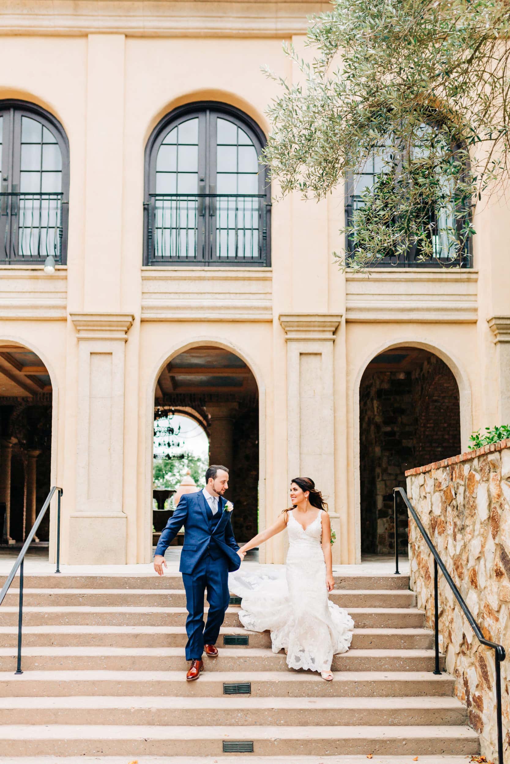 bride and groom running down steps in front of atrium at Bella collina