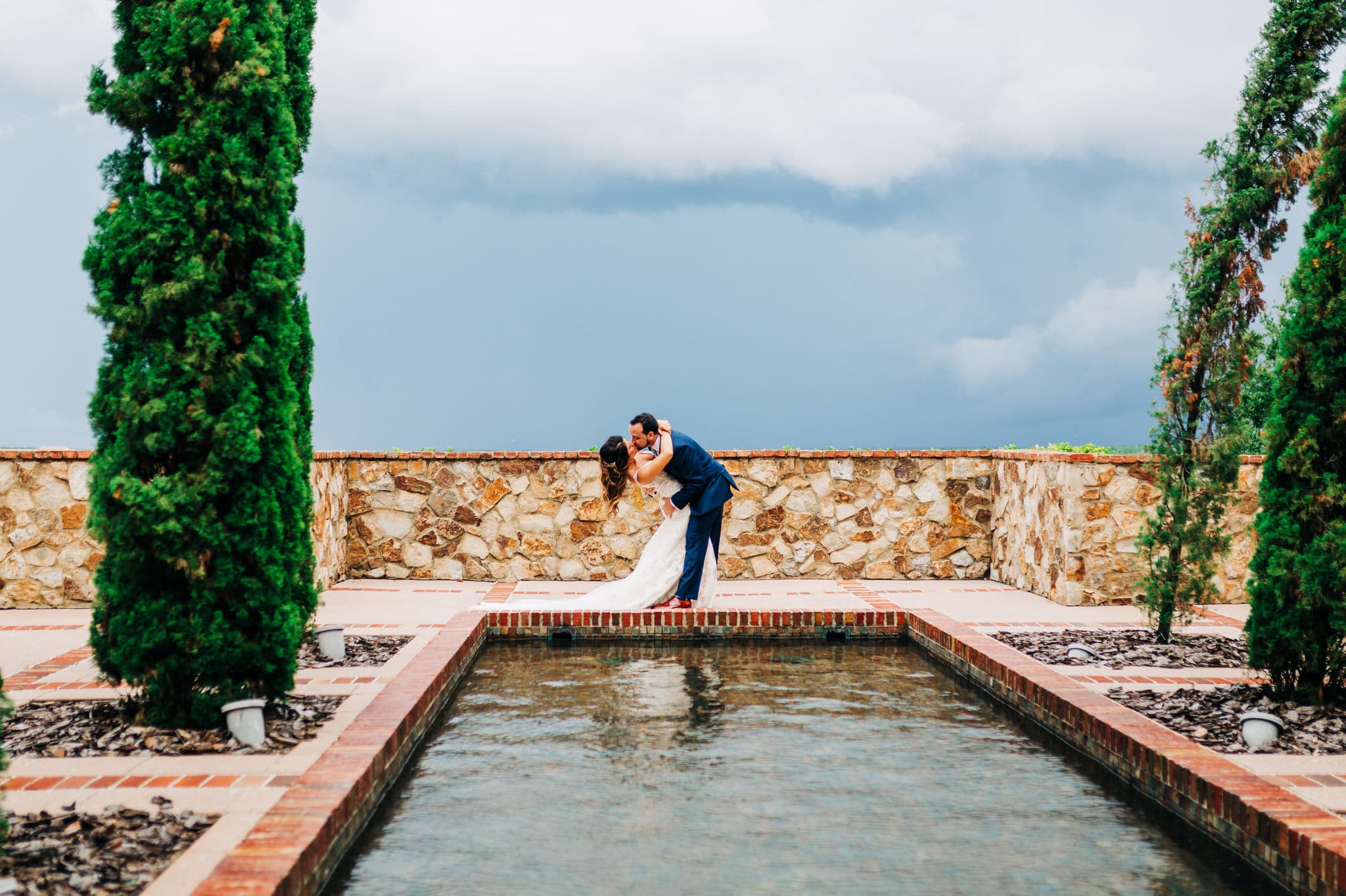 groom kissing and dipping bride at infinity pool at Bella Collina with storm in background