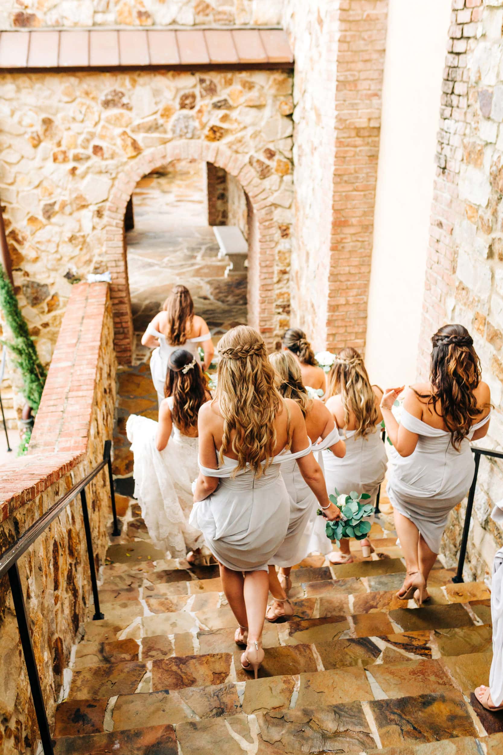 bridesmaids walking down steps to front lawn at Bella Collina in grey dresses