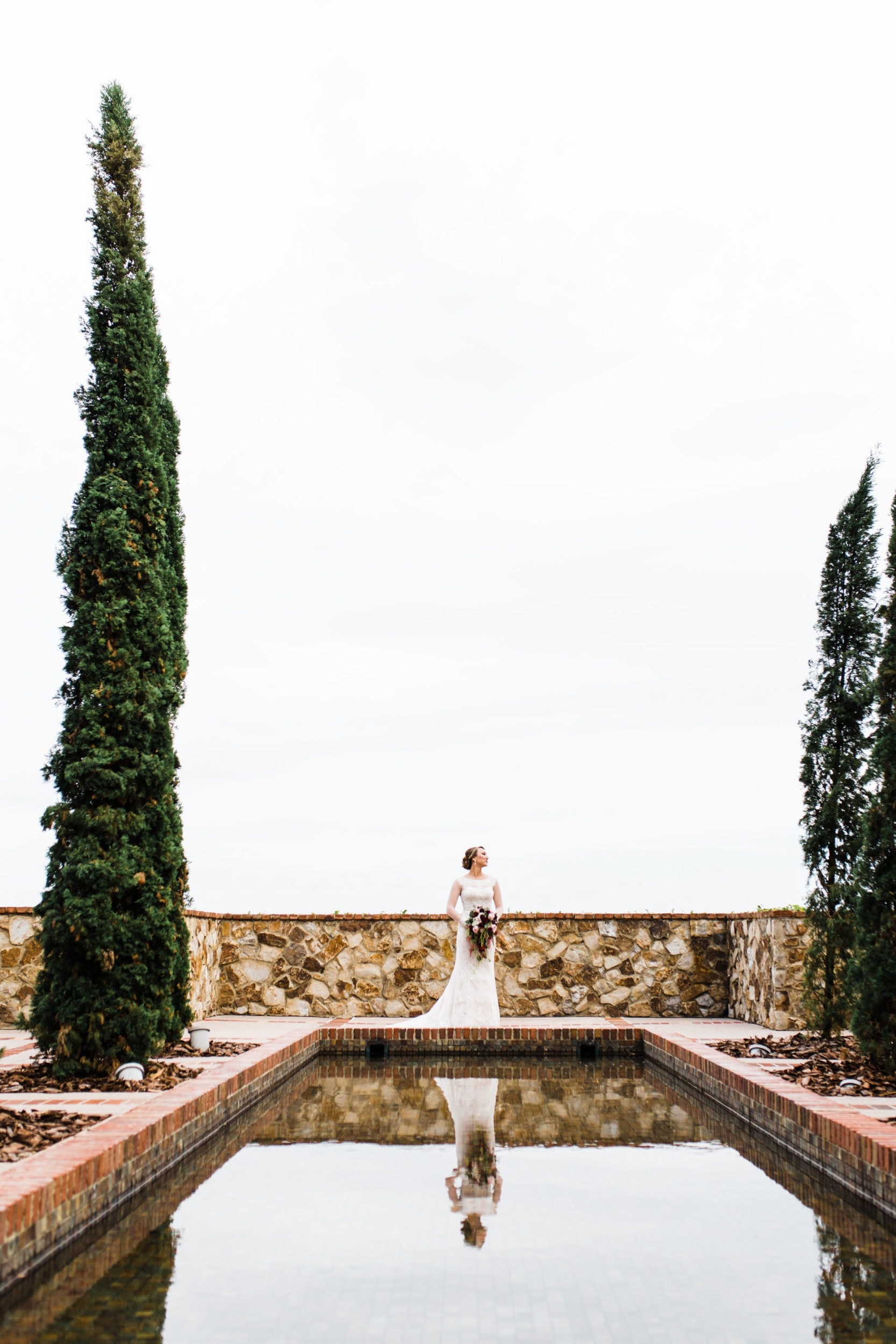 bride standing in front of reflection pool at Bella Collina