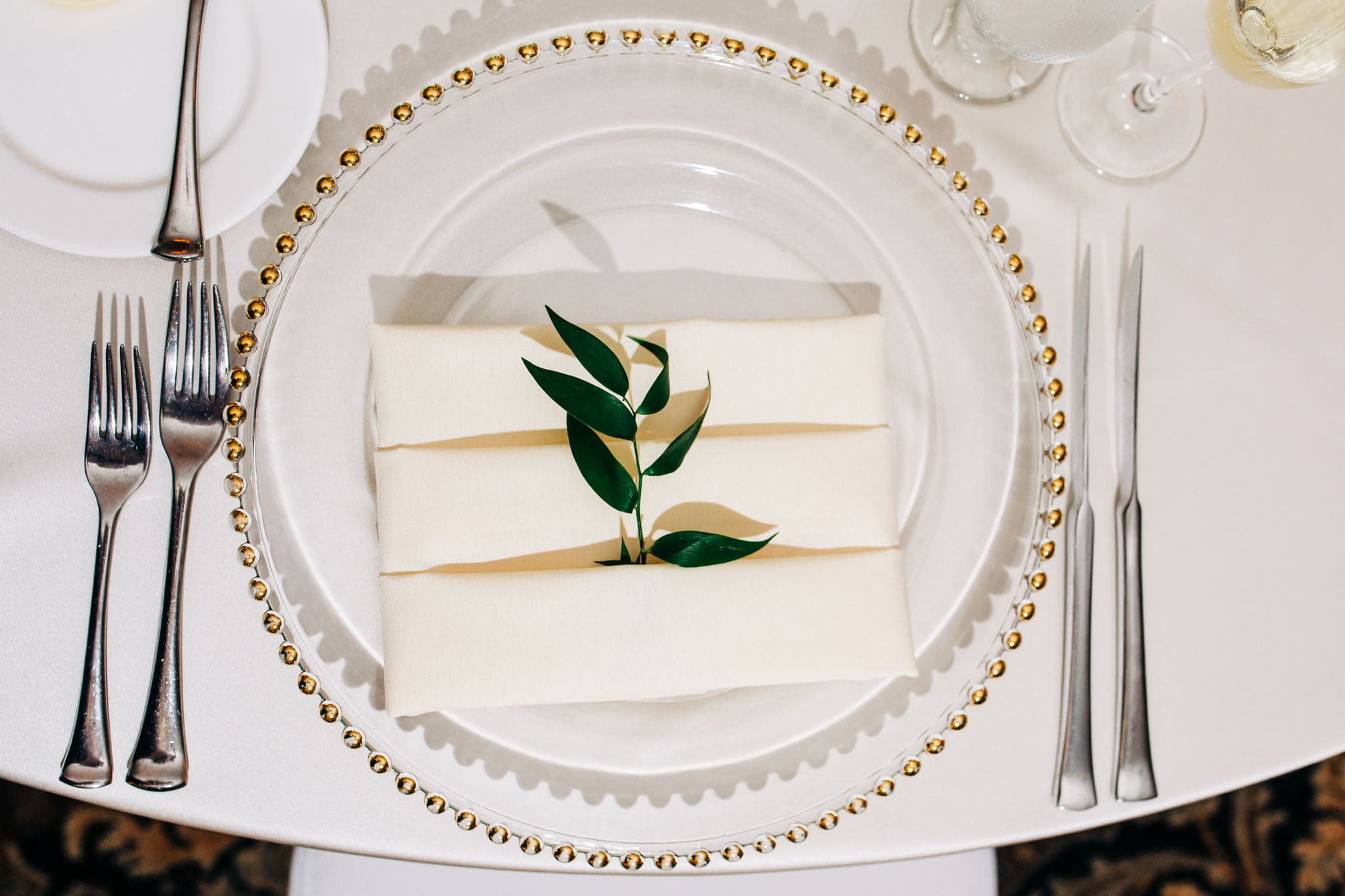 clear plats with white napkins and eucalyptus leaf