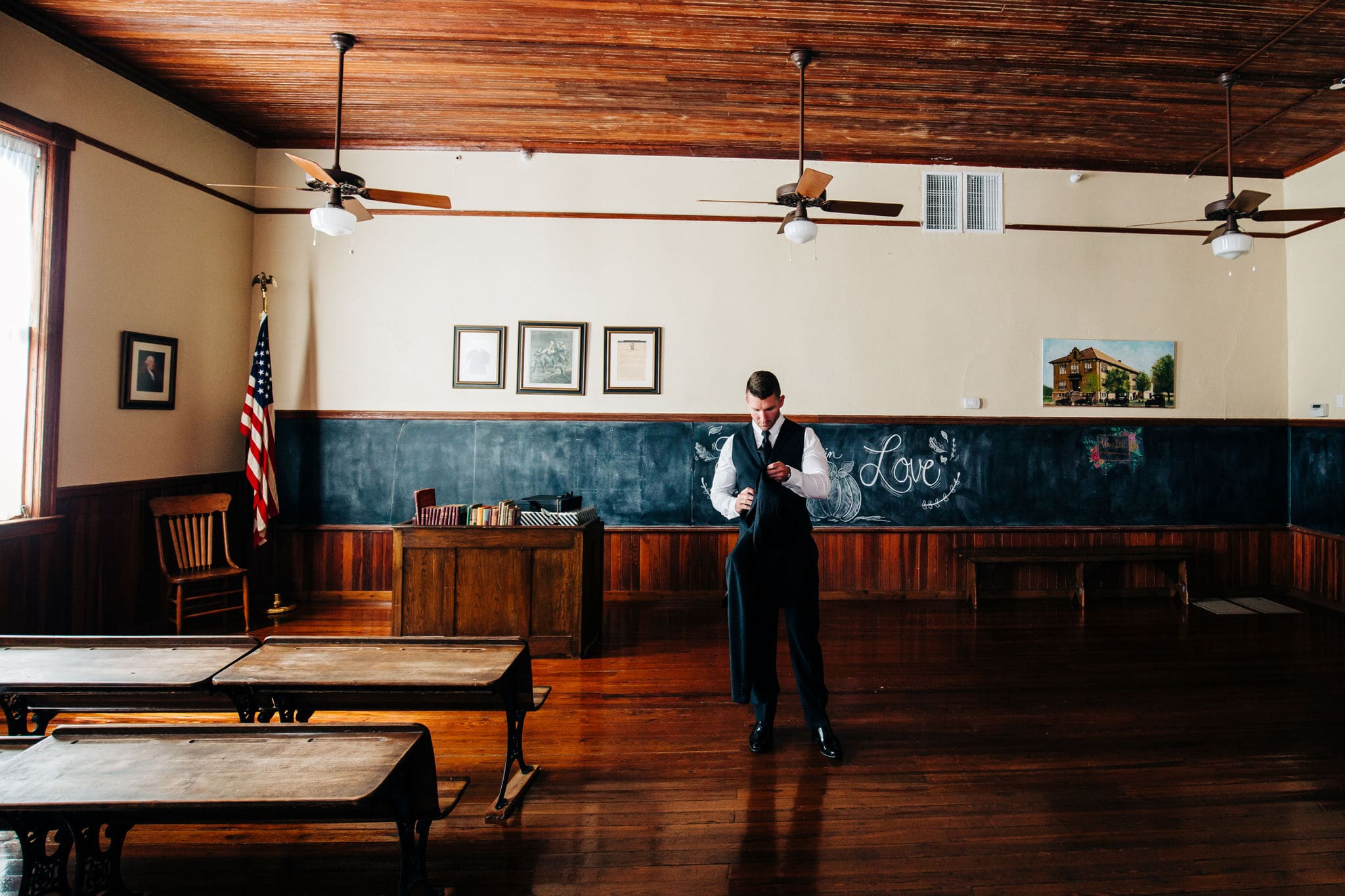 groom getting dressed in vacant classroom at venue 1902 wedding
