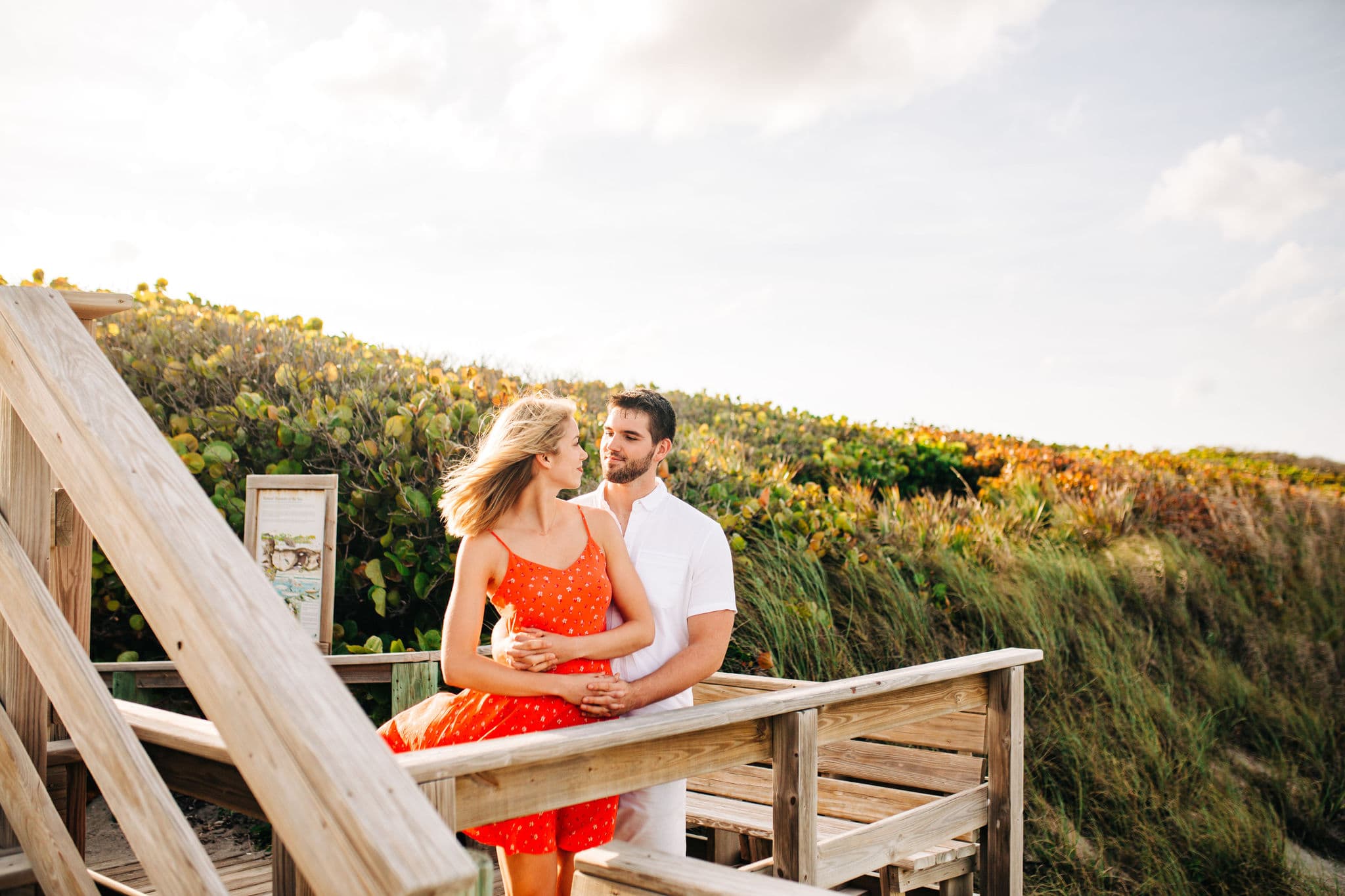 couple standing at the edge of the staircase leading to the ocean with wall of seagrapes behind them