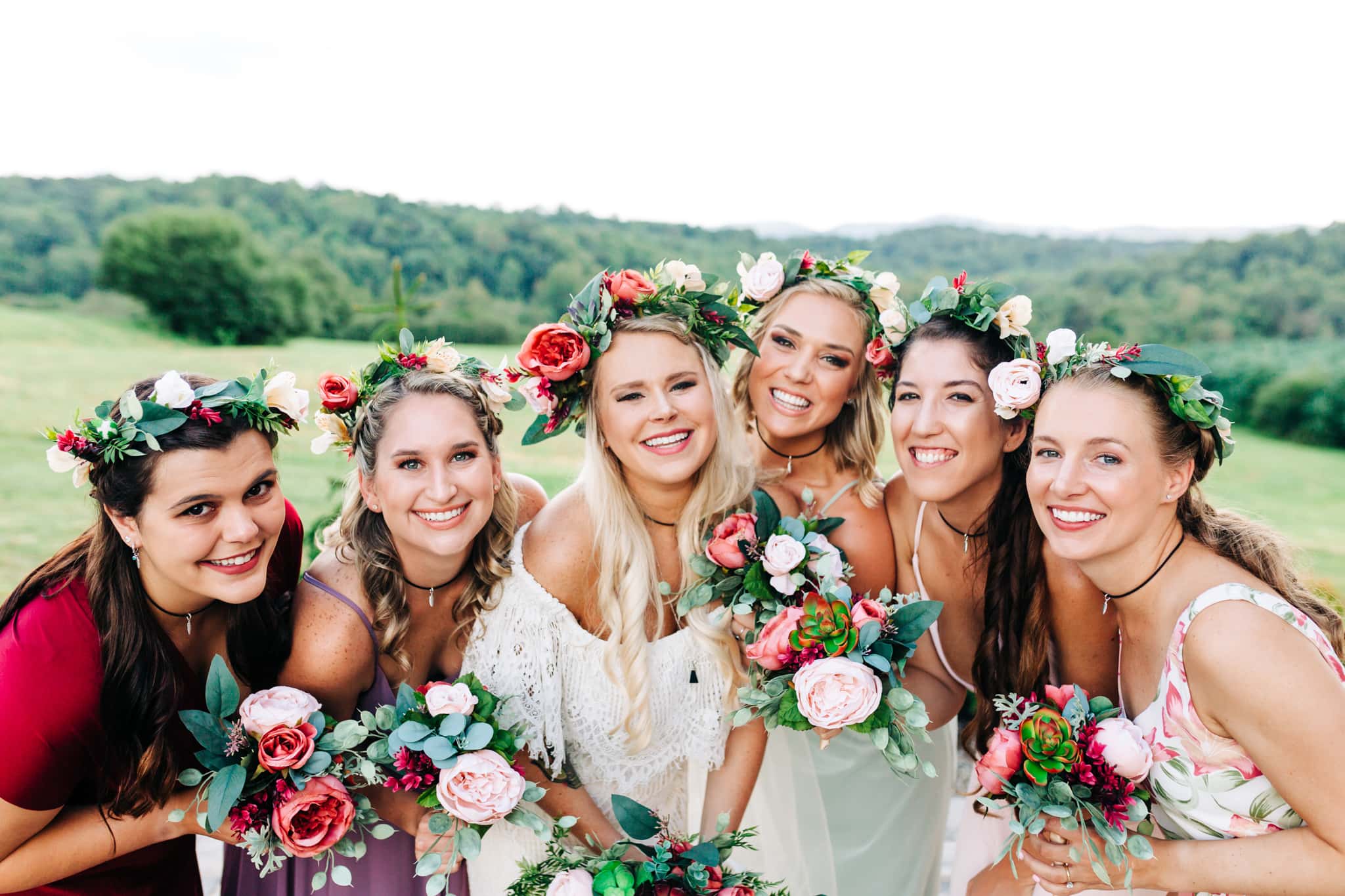 bride and bridesmaids with red white and green boho floral crowns and lace dresses