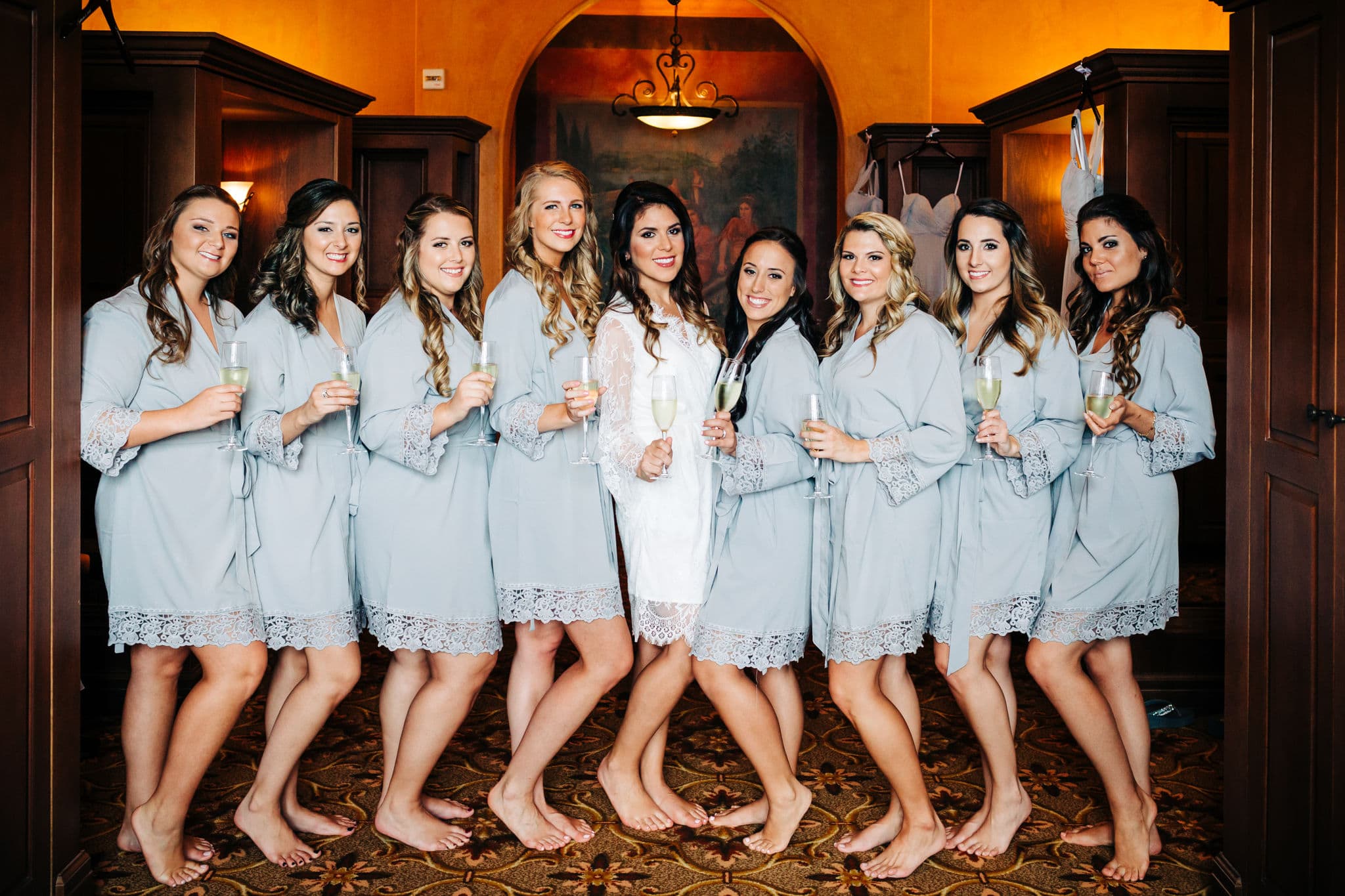 Bride and bridesmaids in grey robes in locker room at Bella Collina wedding venue