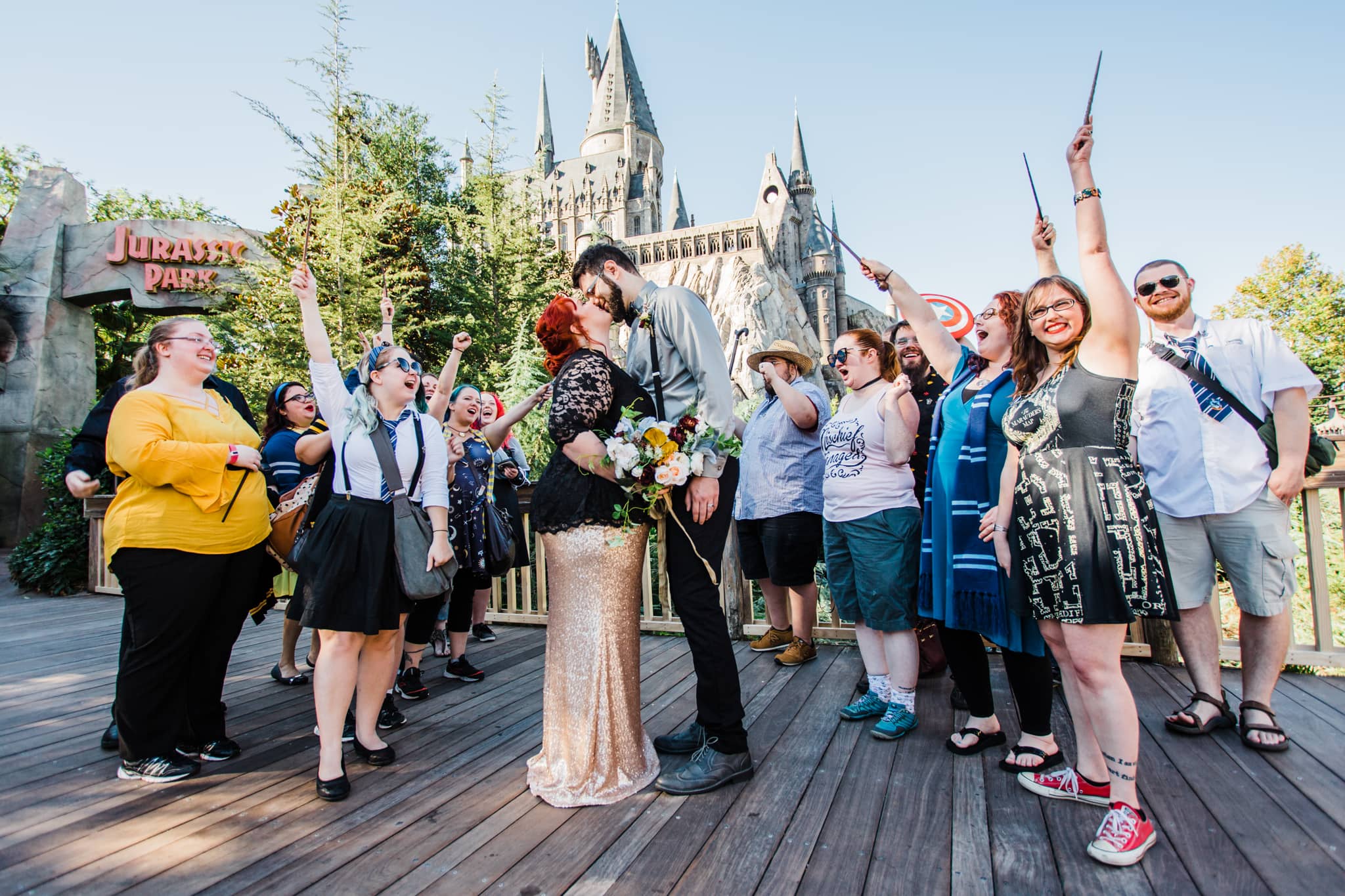 couple renewing vows and kissing in front of Hogwarts castle at universal orlando while surrounded by friends holding up wands