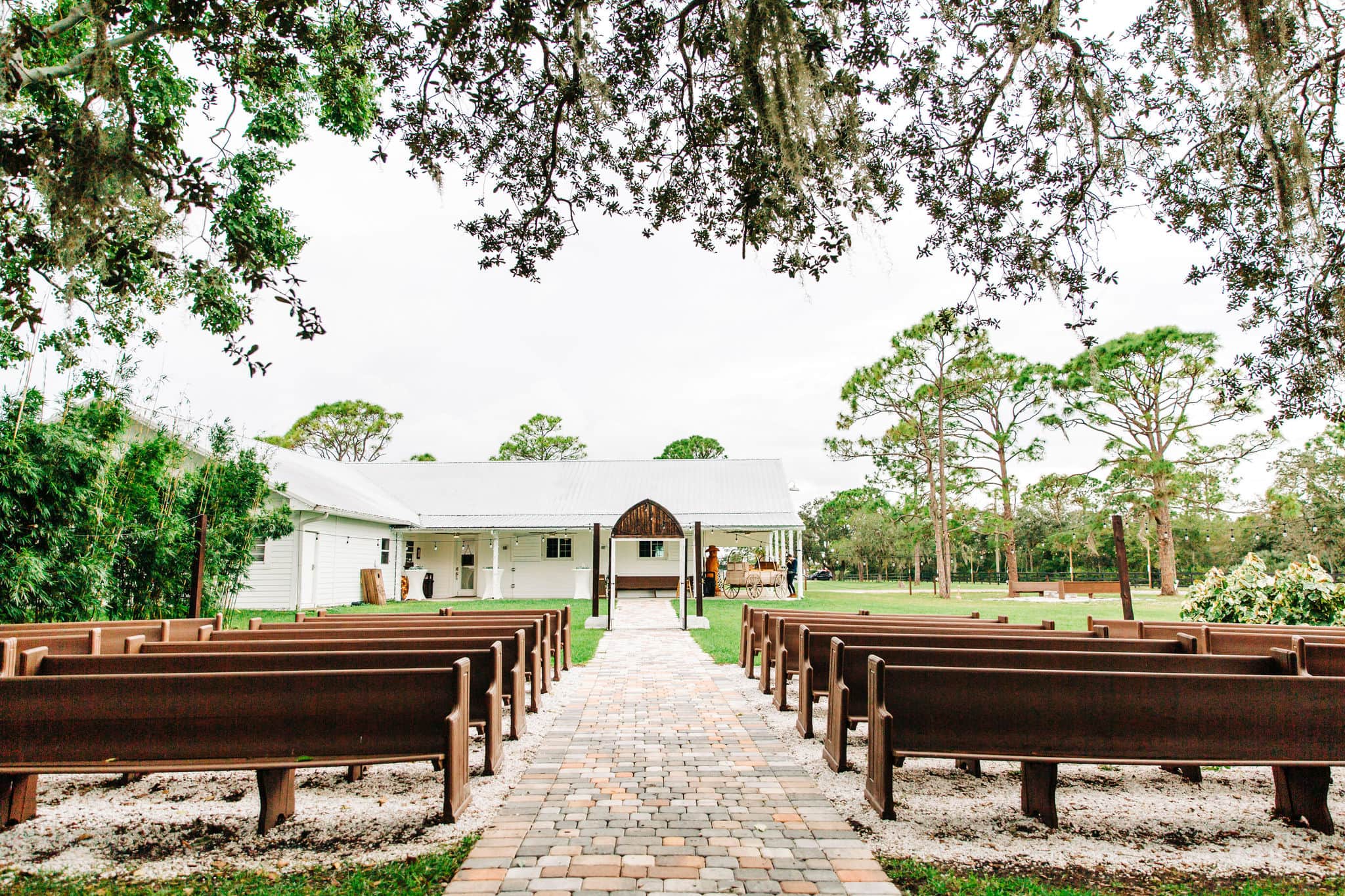 aisle with wooden pews facing a white ranch style building at ever after farms ranch