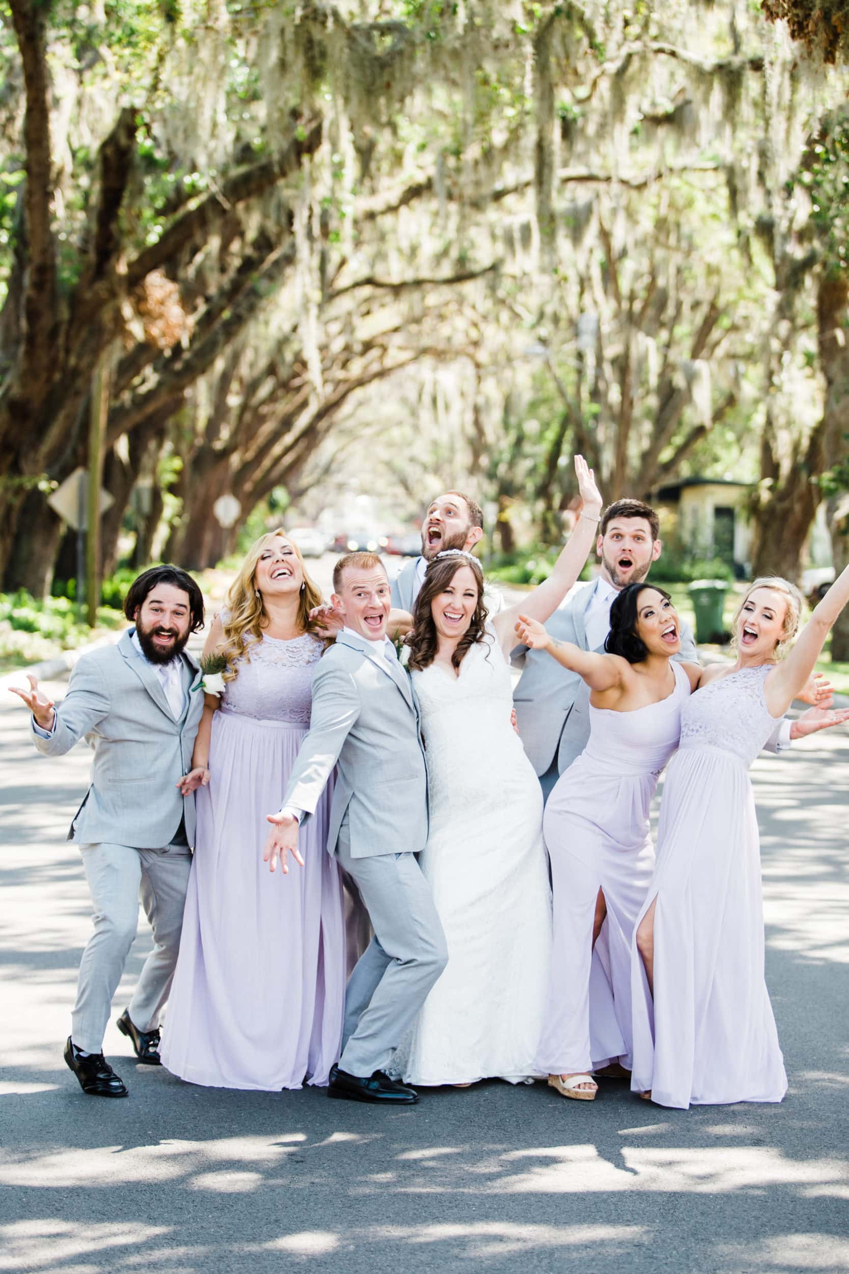 bridal party with lavender dresses with grey suit with large road with large oak tress with spanish moss at castillo de san marcos wedding