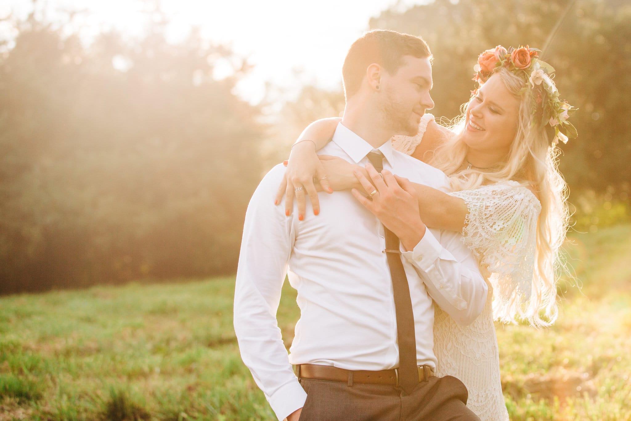 bride hugging groom from behind with golden hour sun in green field at Boho Gambill Estate Wedding 
