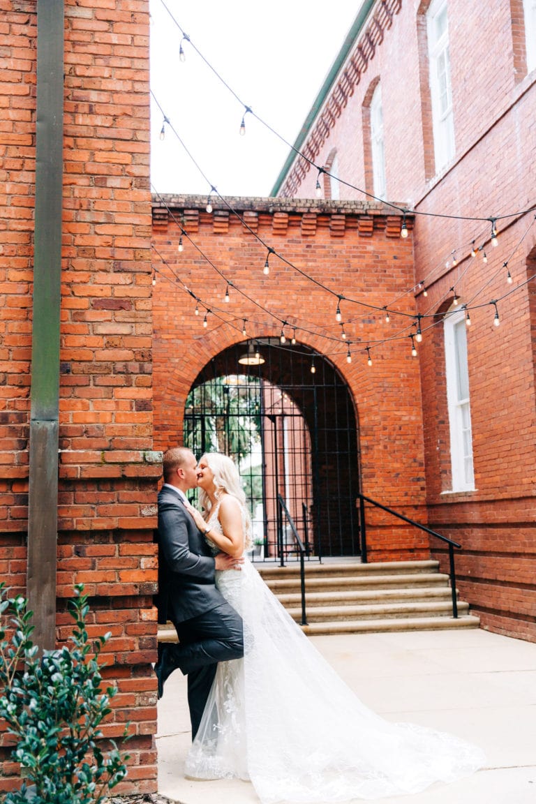 bride and groom with large brick gate entryway at venue 1902 wedding