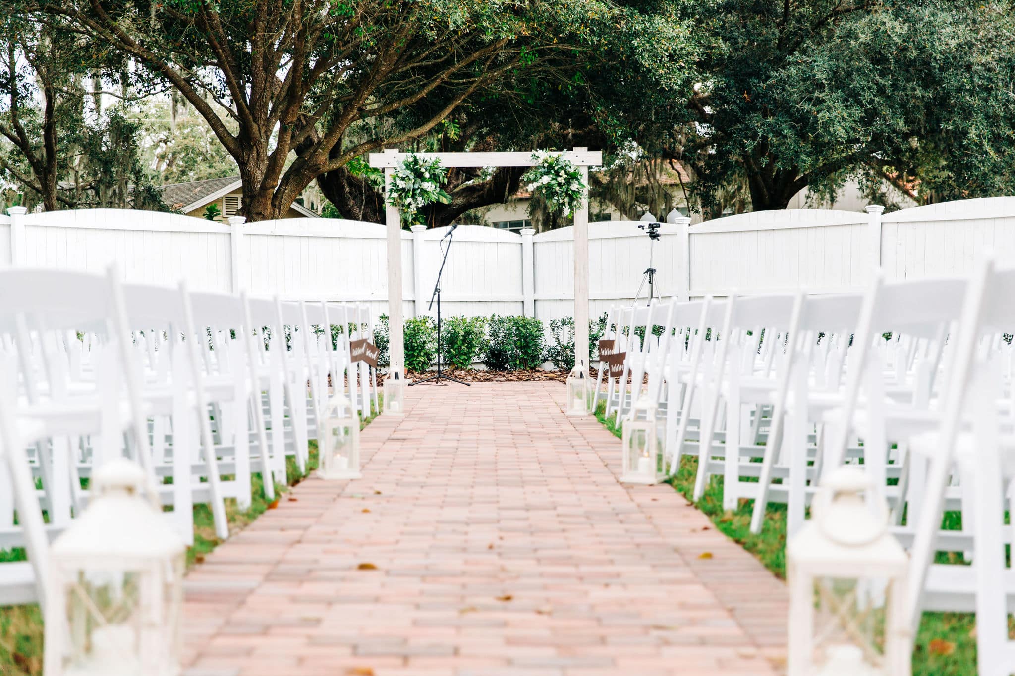 white wooden altar with greenery garland with brick pathway aisle with white chairs at Venue 1902 Wedding