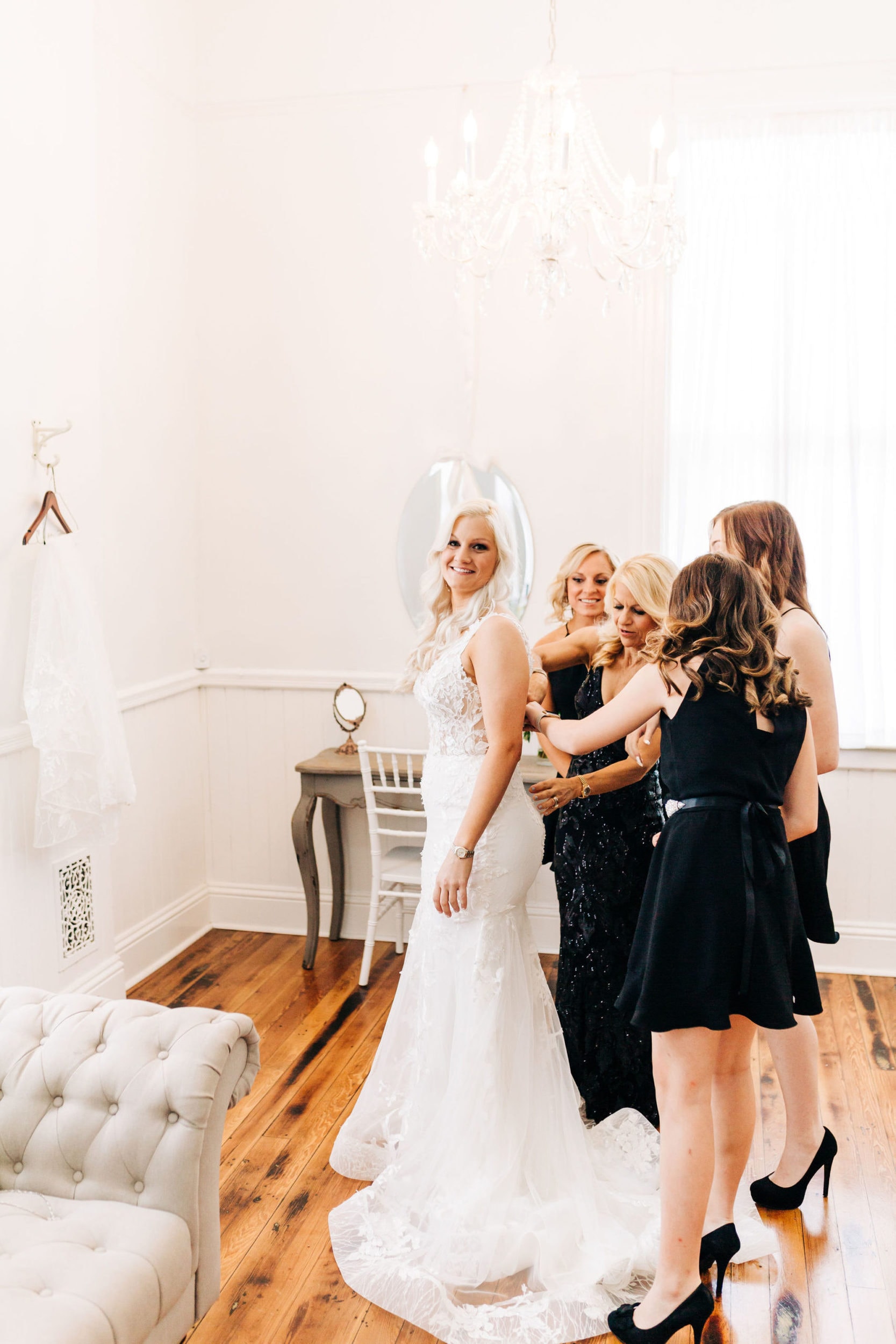 bride with white dress with bridesmaids with black dresses putting on white dress at Venue 1902 Wedding