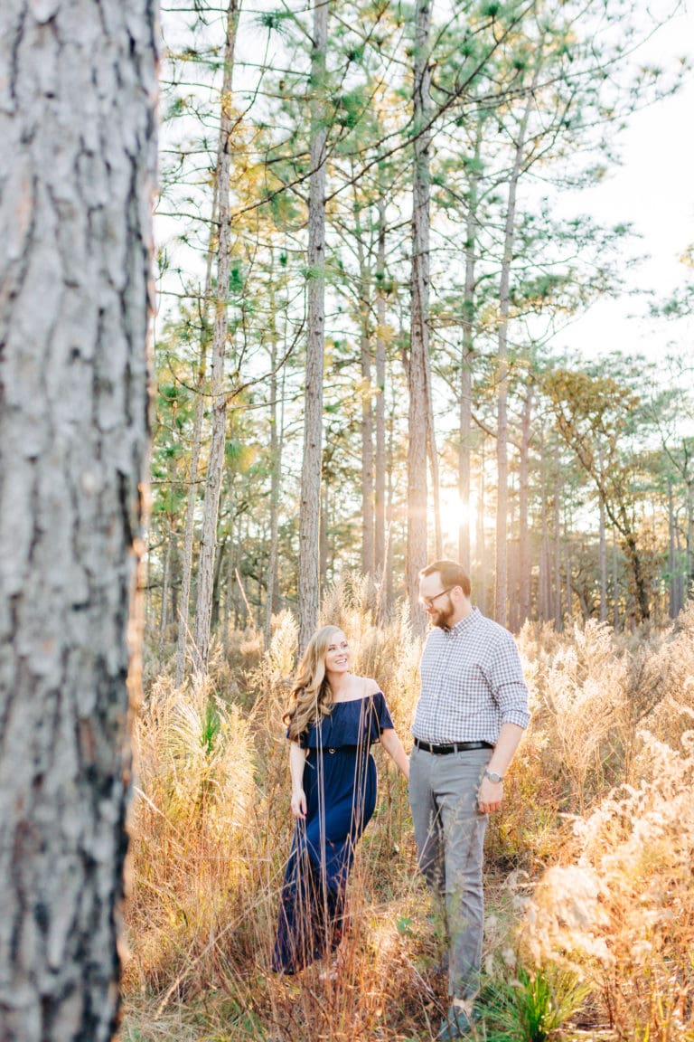 bride to be with groom to be with navy and grey outfits walking through woods at Wekiwa Springs State Park Engagement Session