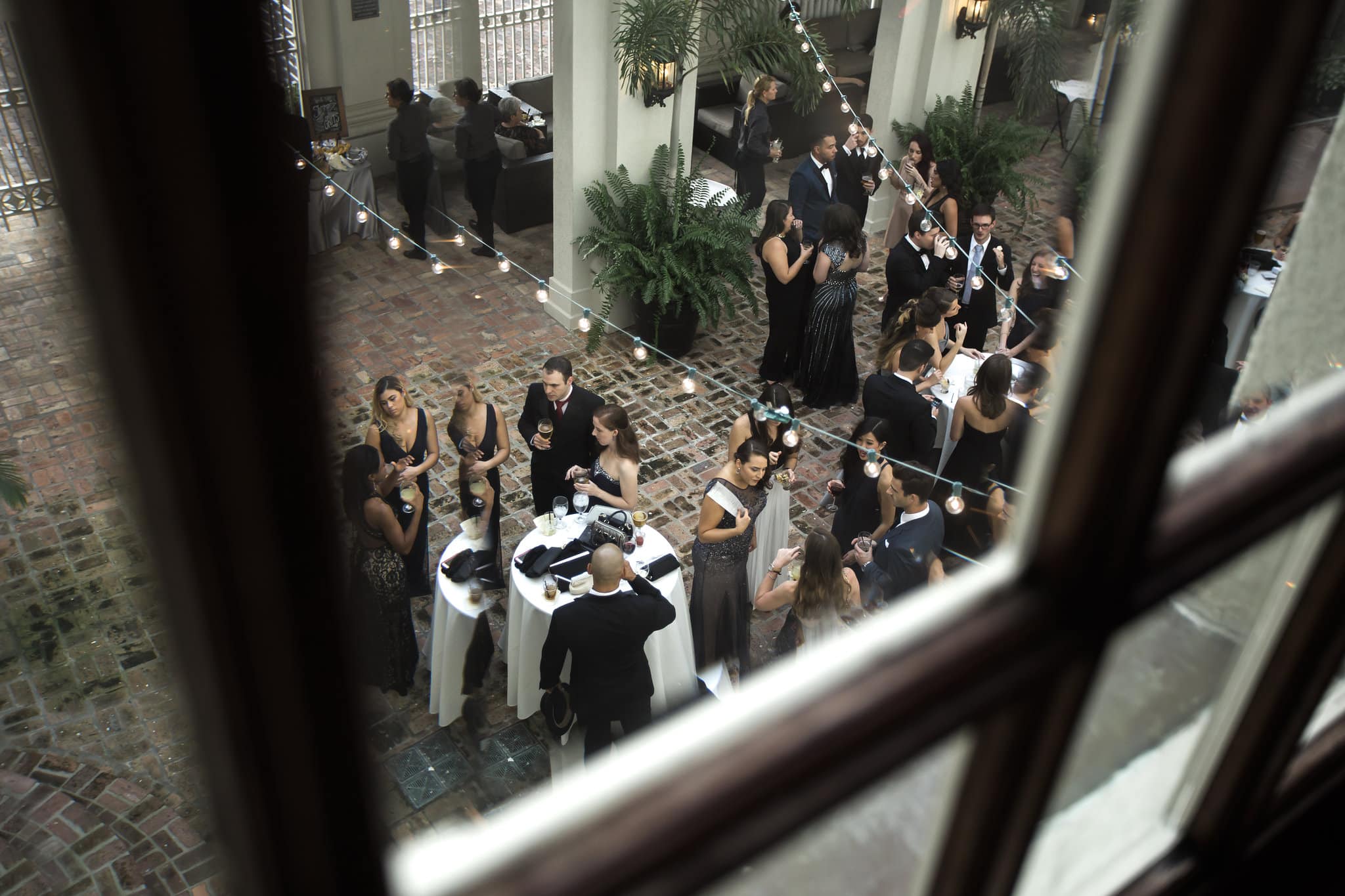 looking through window to courtyard with string lights and cocktail tables with wedding guests at Star Wars Wedding